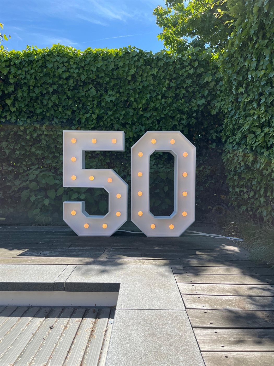 Lichtcijfer 50 overdag in de tuin bij een heg